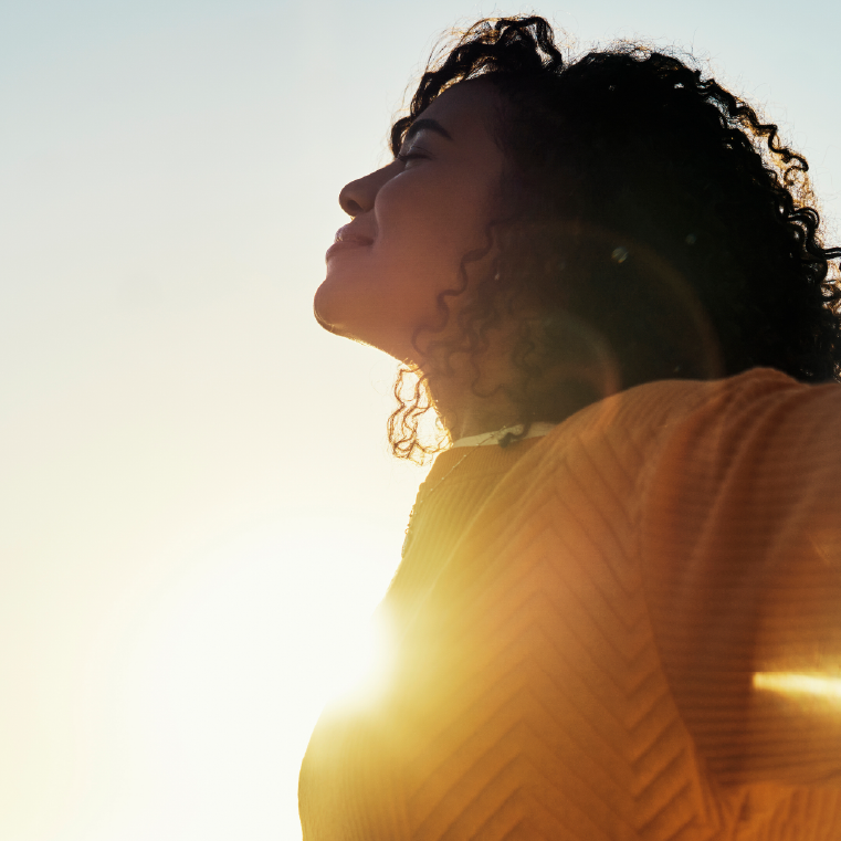 Woman in yellow shirt feeling well after adjusting her medas following a DNA test with the sun in the background