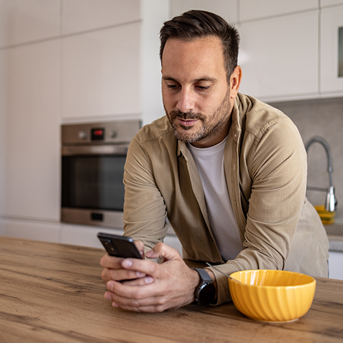 Middle-aged man filling the microbiome recommandation tool form on his smartphone in his kitchen
