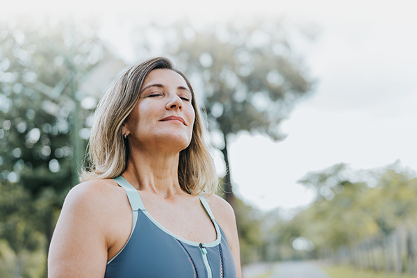 A woman in athletic wear taking a break and enjoying feeling relieved from pain or medication side effects