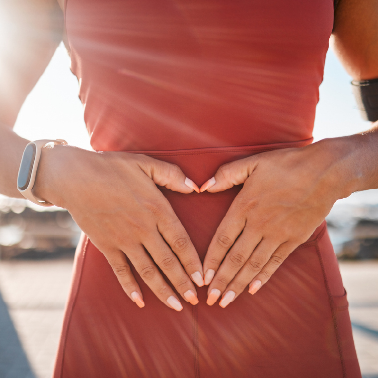 Woman in red dress holding hands on her belly to show she takes care of her gut health and microbiome 