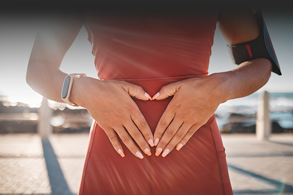 Woman in sports outfit with her hand on her belly to show she takes care of the microbiote and gut flora