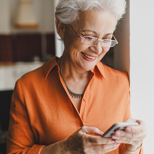 Elderly woman smiling when looking at her smartphone and looking at her test results in her MyBiron health portal
